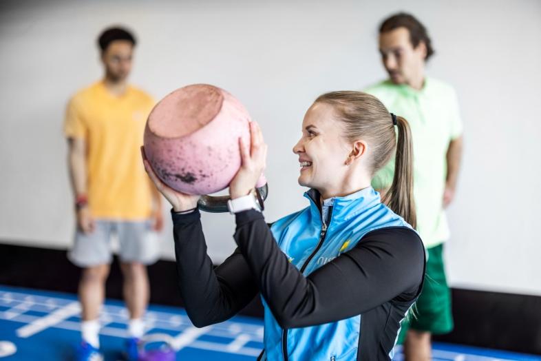 Kolme henkilöä jumppaa kahvakuulan kanssa